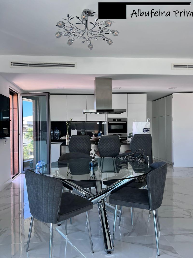 Round glass dining table with six chairs in front of the kitchen