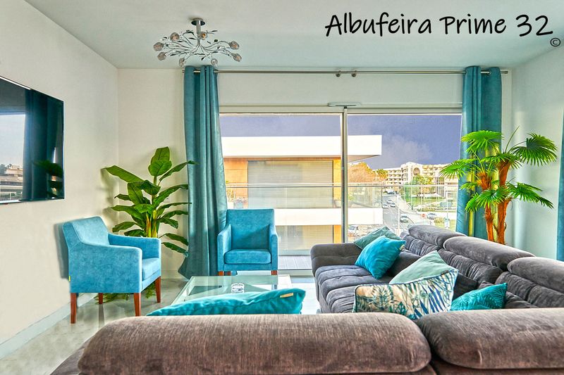 Living room with sofa, two blue armchairs and doors to the balcony